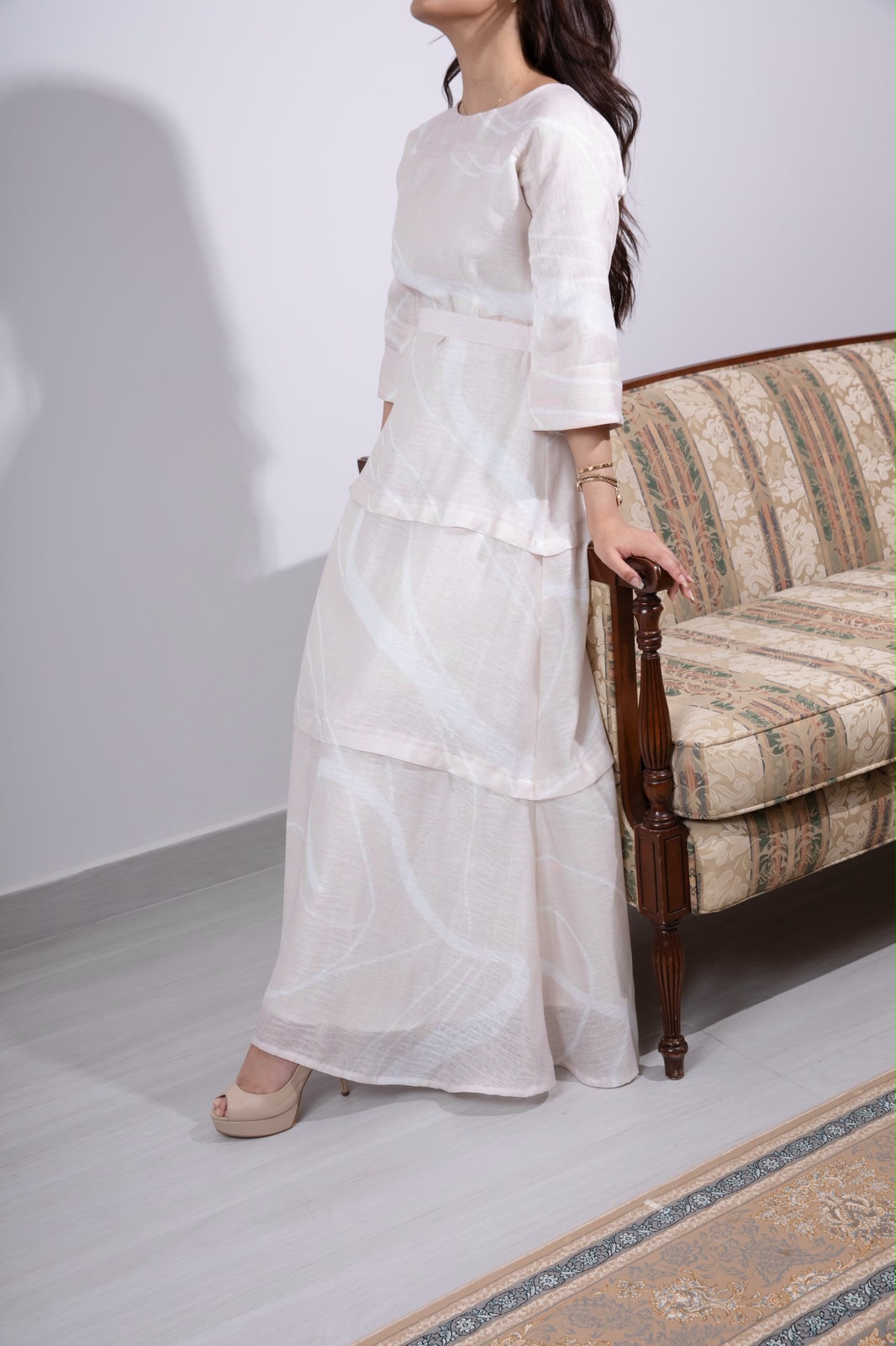 Blush brushstroke tiered dress styled on an antique sofa in the Appliqué Manama atelier
